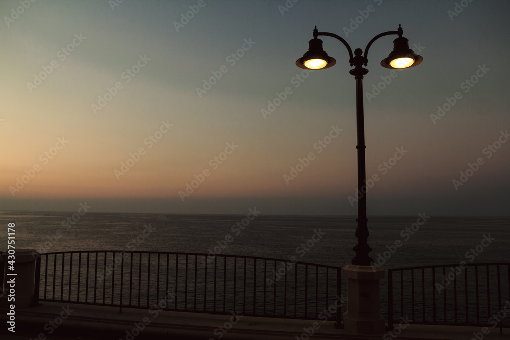 Street lamp at sunset on the background of the sea