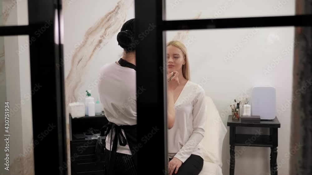 Beautician using pencil to create contour on woman lips before tattoo procedure.