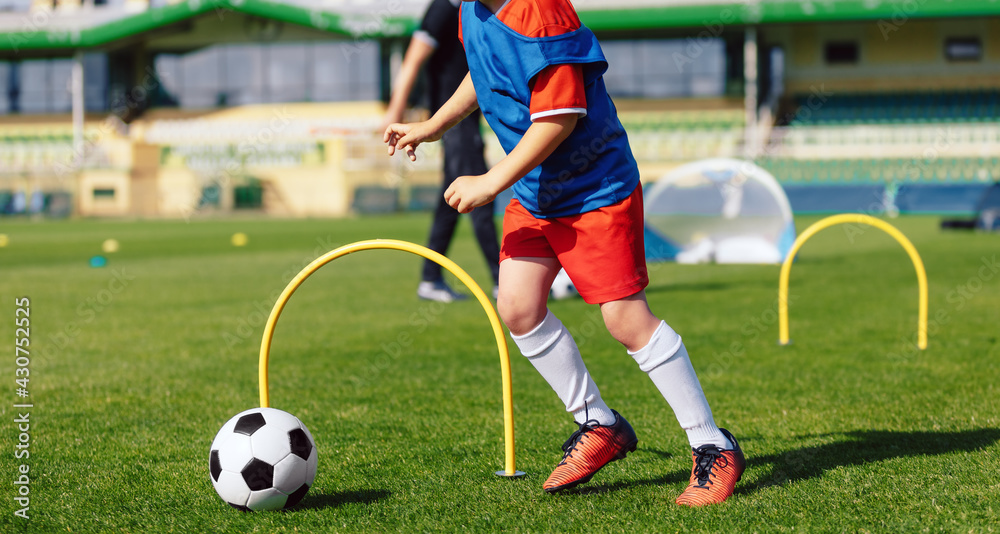 Obraz premium Child playing soccer ball on practice unit. School physical education class for kids. Football sports training camp. Exercise class for sporty boys