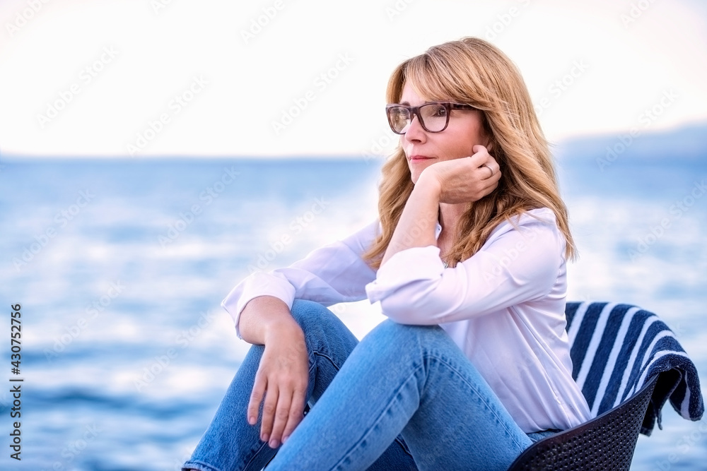 Portrait of woman deep in thought while sitting by the sea