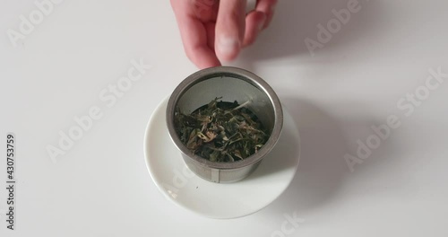 Bulk tea leaves in a metal tea filter being picked up. photo