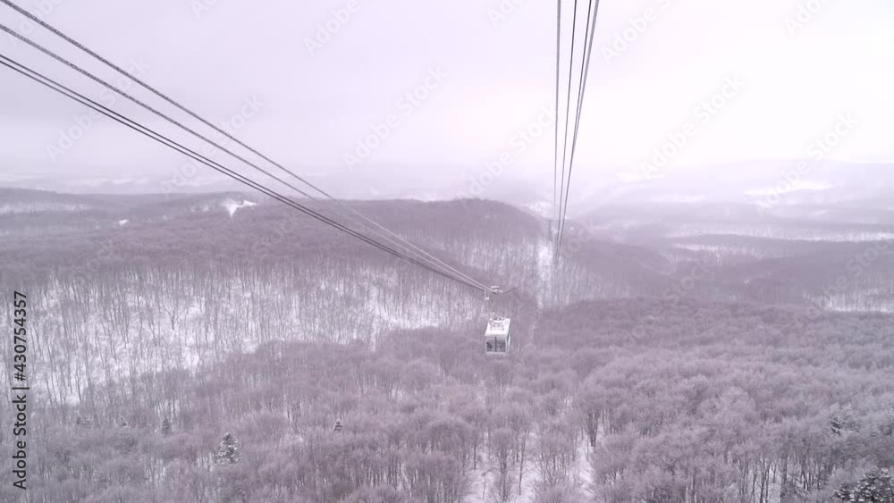 Slow motion view of beautiful winter landscape with snowy cable cars and forest