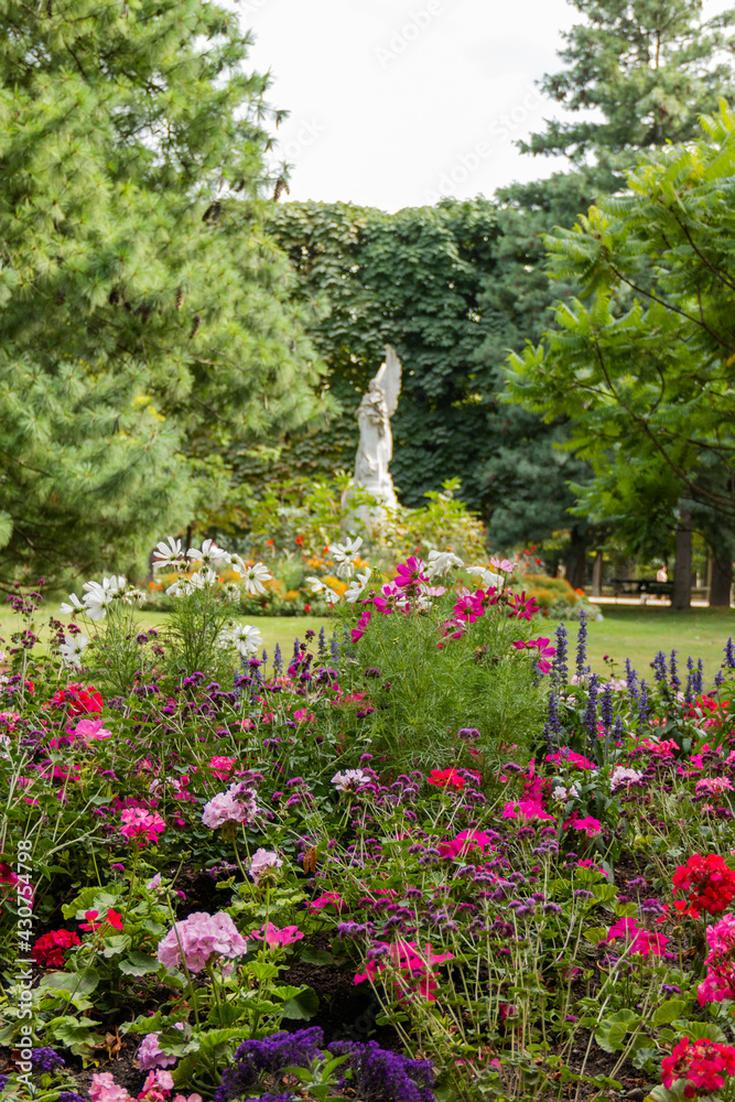 Beautiful and colorful flowers with the statue of an angel as background