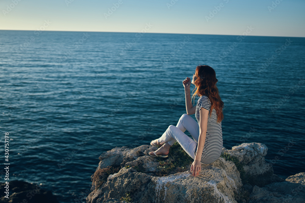 the traveler sits on the beach near the sea in the mountains and sunset