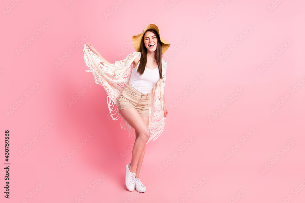 Full length photo of charming positive girl arms hold playing with clothes isolated on pink color background