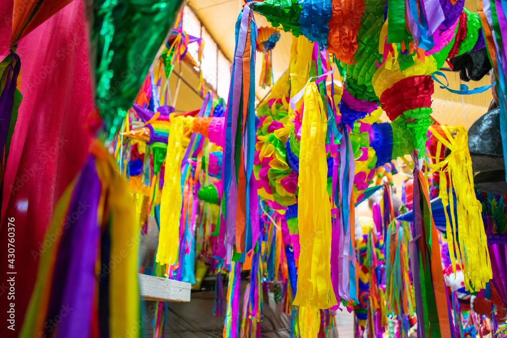 Colorful pinatas with paper stripes hanging inside a market