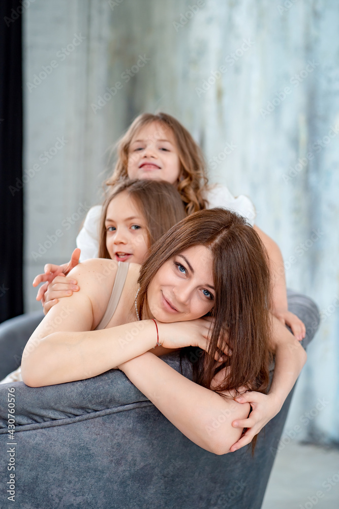Mom cuddles with her daughters. happy family. 