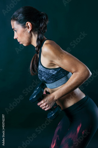 Woman performing fitness exercises isolated on dark background.