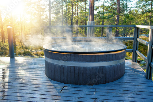 Modern big barrel outdoor hot tub in the middle of forest. The hot tub's soothing warm water relaxes muscles and eases tensions, so your worries can simply melt away.