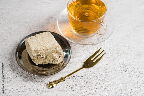 Dessert halva made from sunflower seeds with a cup of green tea on a light background. Vegan product photo