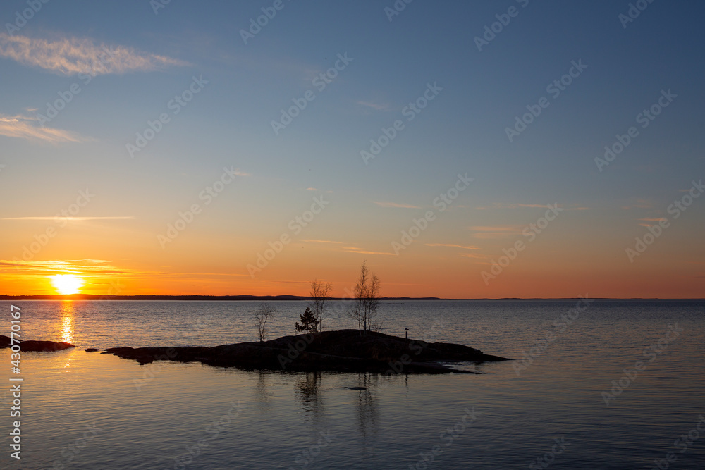 Colorful and calm sunset landscape in Finland. Glowing sky with silhouette trees.