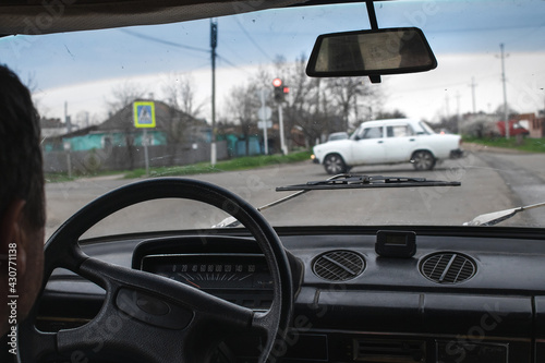 The man in the car. Male driver at the wheel. The driver in the car stands at the intersection, waiting for the green light and looks at the road through the glass, a first-person view.