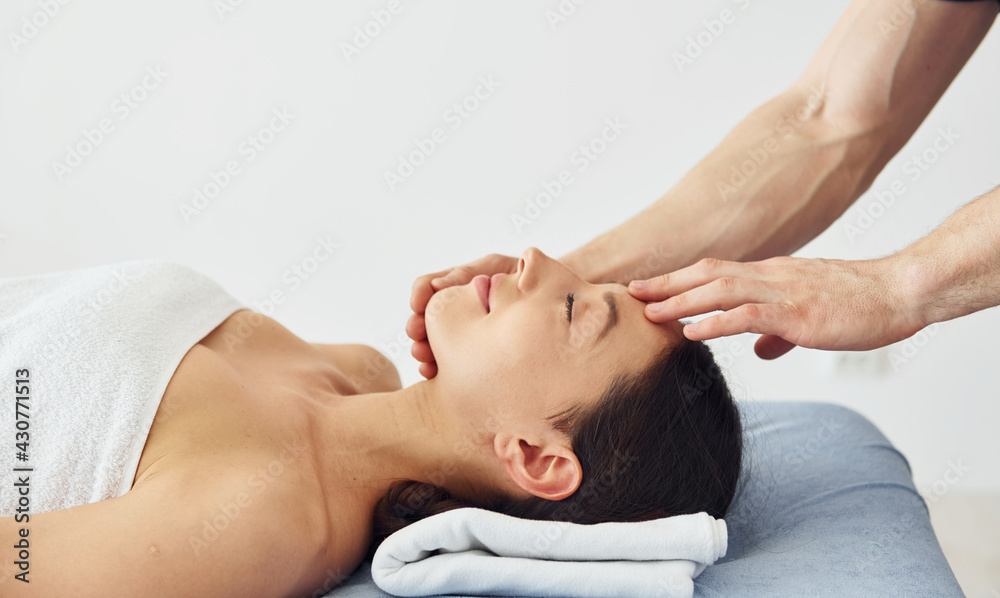 Head massage. Young woman is lying down when man doing procedure to her in spa Head massage. Young woman is lying down when man doing procedure to her in spa