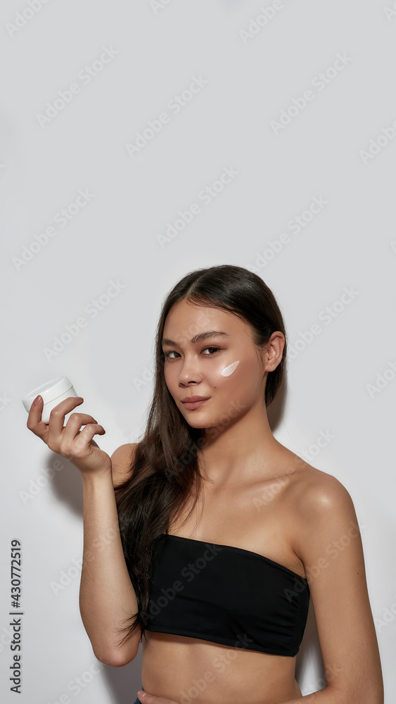 Young asian girl holding facial cream jar on palm Young asian girl holding facial cream jar on palm