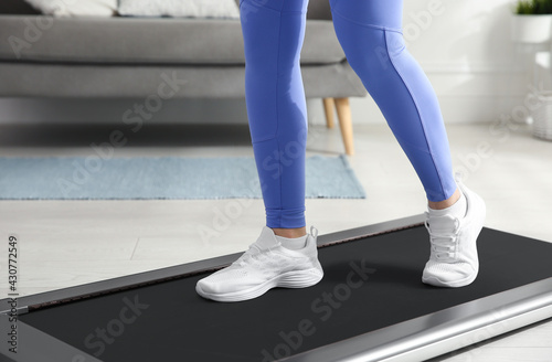 Sporty woman training on walking treadmill at home, closeup