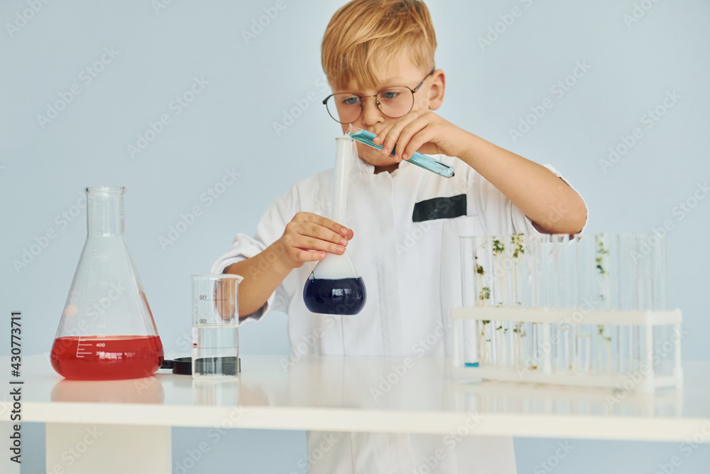Little boy in coat playing a scientist in lab by using equipment Little boy in coat playing a scientist in lab by using equipment