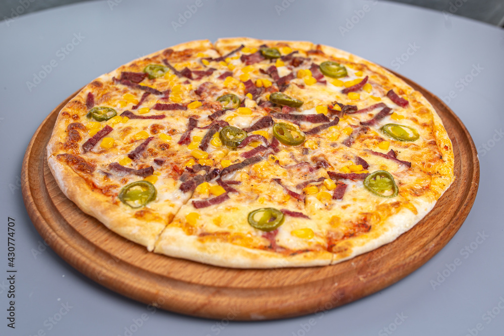 pizza with peppers and sausages on a wooded board