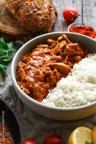 Traditional curry and ingredients. Tikka Masala chicken and rice. Indian food. Close up. Copy space. Wooden background.