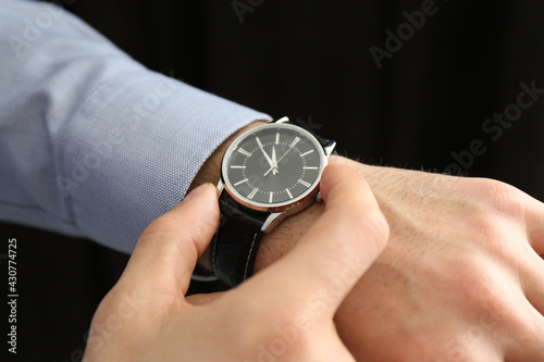 Man with luxury wrist watch on black background, closeup