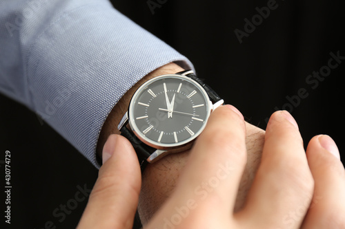 Man with luxury wrist watch on black background, closeup