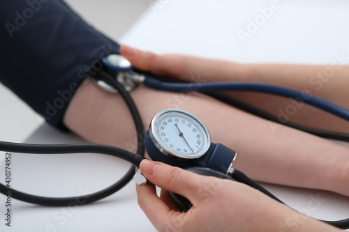 Doctor checking blood pressure of woman in clinic, closeup