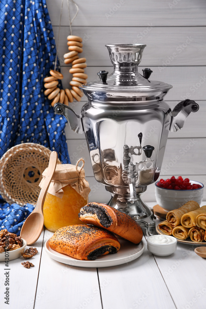 Traditional Russian samovar and treats on white wooden table