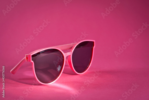 Sunglasses on a pink background. Women's glasses close up. Copy space and place for text near the glasses.