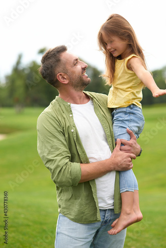 Excited little girl having fun with her father while he is holding her and smiling, daughter and daddy spending time together outdoors © Kostiantyn