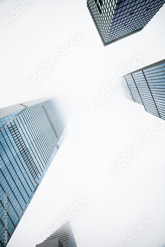 Modern glass skyscrapers reaching into the cloudy white sky
