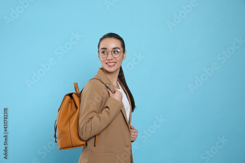 Beautiful young woman with stylish leather backpack on turquoise background. Space for text