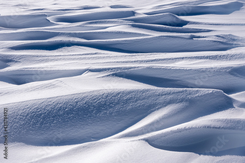 Perfect abstract texture of winter snow, mounds of frozen blue snow. Wavy surface of firn field