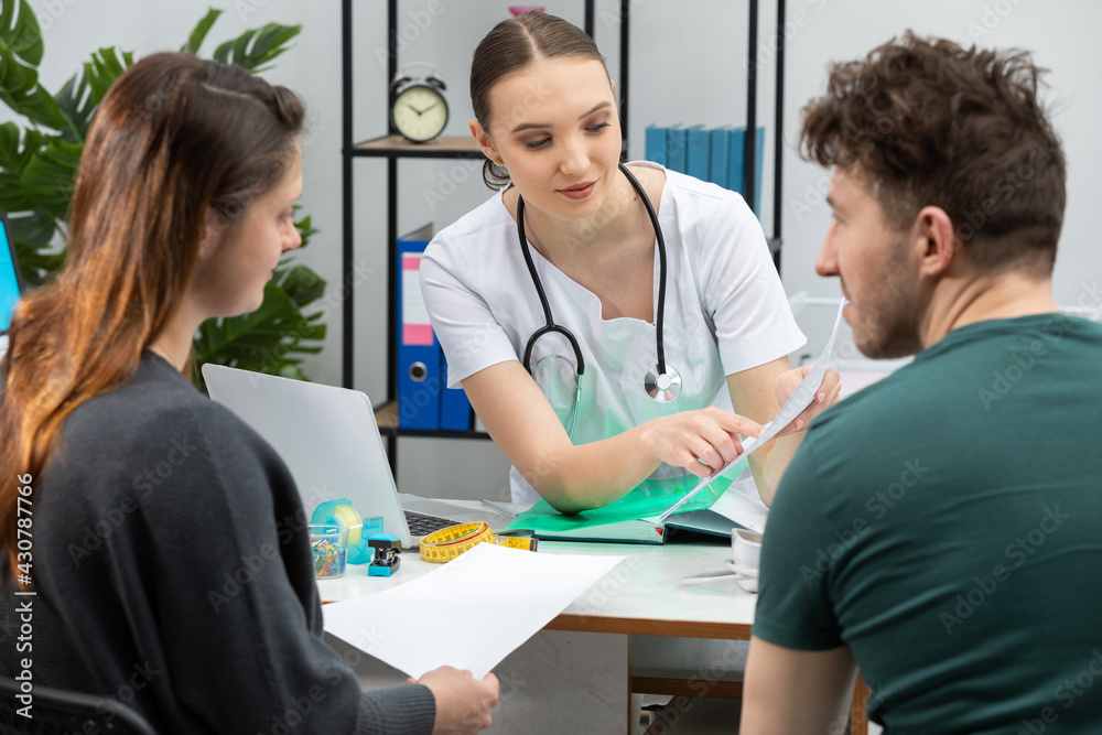 Obraz premium A gynecologist is explaining test results to a pregnant patient. A married couple in the gynecologist's office.