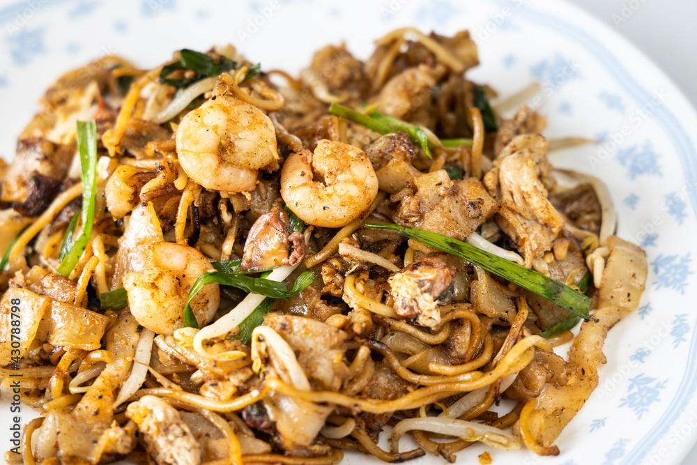 Close-up on Penang char kuey teow is popular fried noodle with coceral, shrimp and eggs in black sauce in Malaysia Close-up on Penang char kuey teow is popular fried noodle with coceral, shrimp and eggs in black sauce in Malaysia