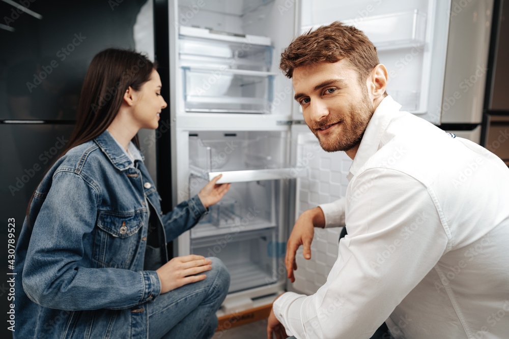 Obraz premium Young couple selecting new refrigerator in household appliance store