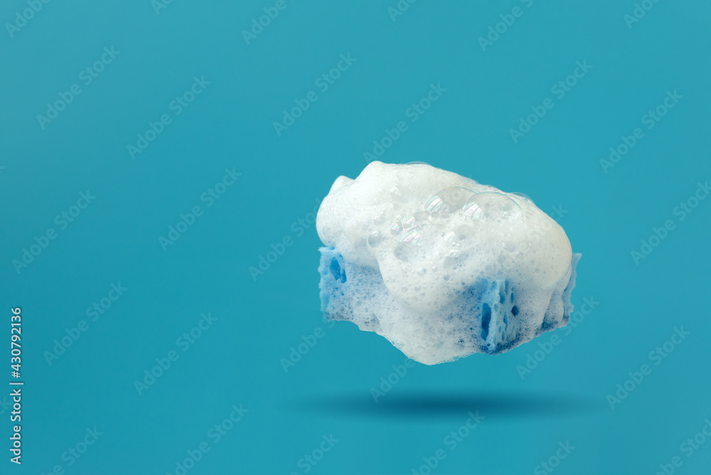 Blue kitchen cleaning sponge with soap bubbles on blue background. Front view Blue kitchen cleaning sponge with soap bubbles on blue background. Front view