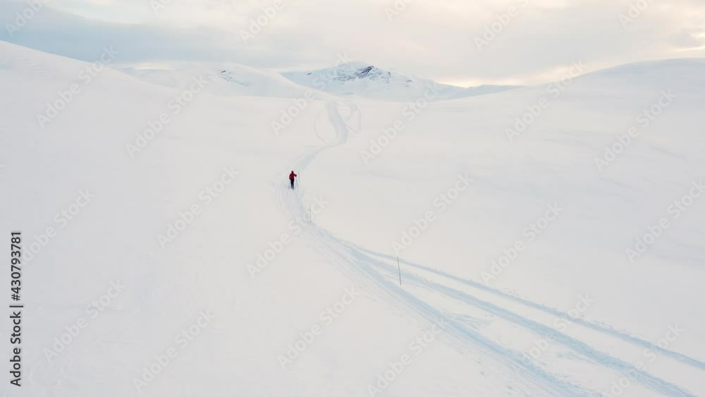 Cross country skier traveling across a snowy arctic tundra in the high mountains on a cold winters day. Cross country skier traveling across a snowy arctic tundra in the high mountains on a cold winters day.