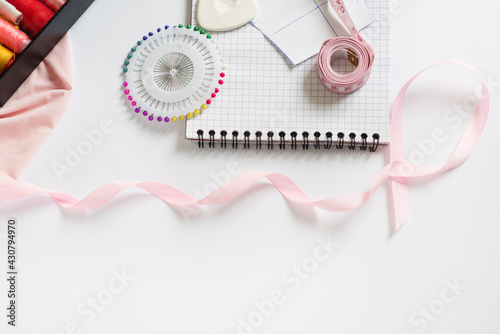 Tools for cutting and sewing. Seamstress kit. Multi-colored reels of threads, tape, needles on a white background. Frame, space for text
