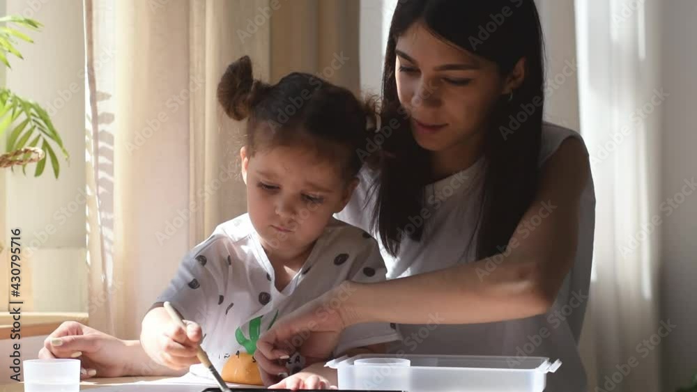 A dark-haired mixed race woman paints together with her daughter at home.Family concept.Time together.Slow motion A dark-haired mixed race woman paints together with her daughter at home.Family concept.Time together.Slow motion