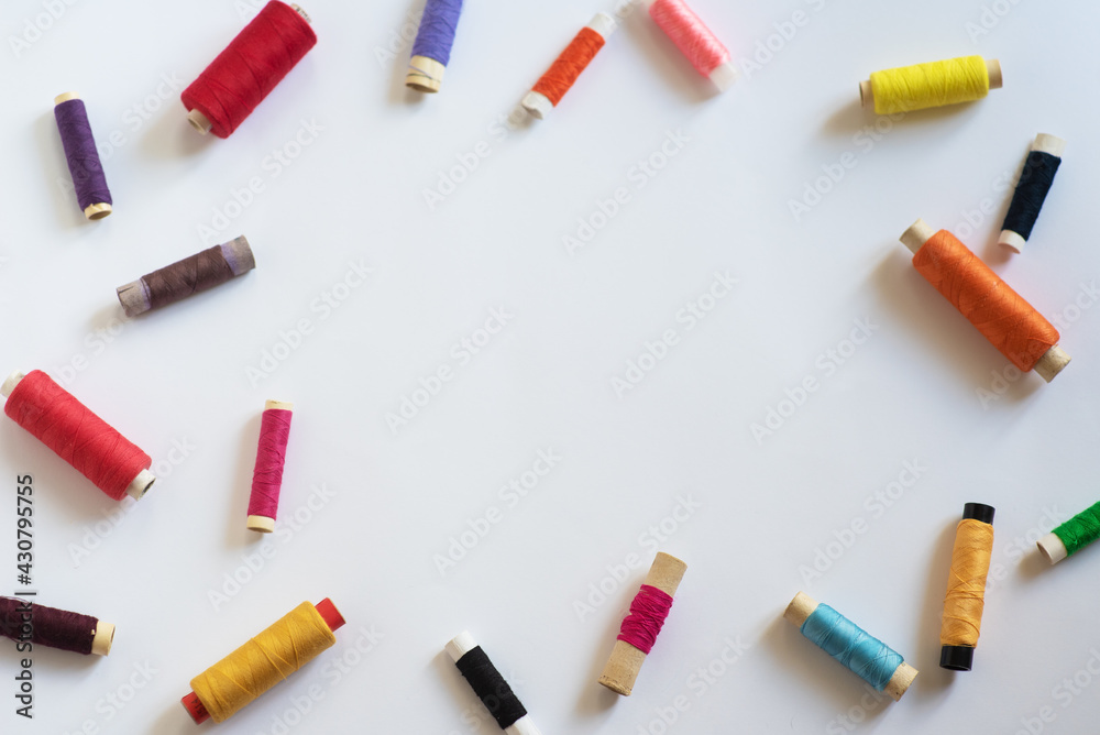 Frame with multi-colored reels with threads on a white background. Top View Frame with multi-colored reels with threads on a white background. Top View