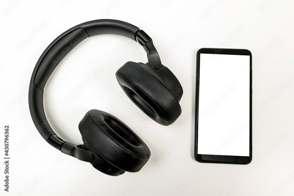 headphones with Bluetooth technology on white background, with black phone paired for music lovers headphones with Bluetooth technology on white background, with black phone paired for music lovers