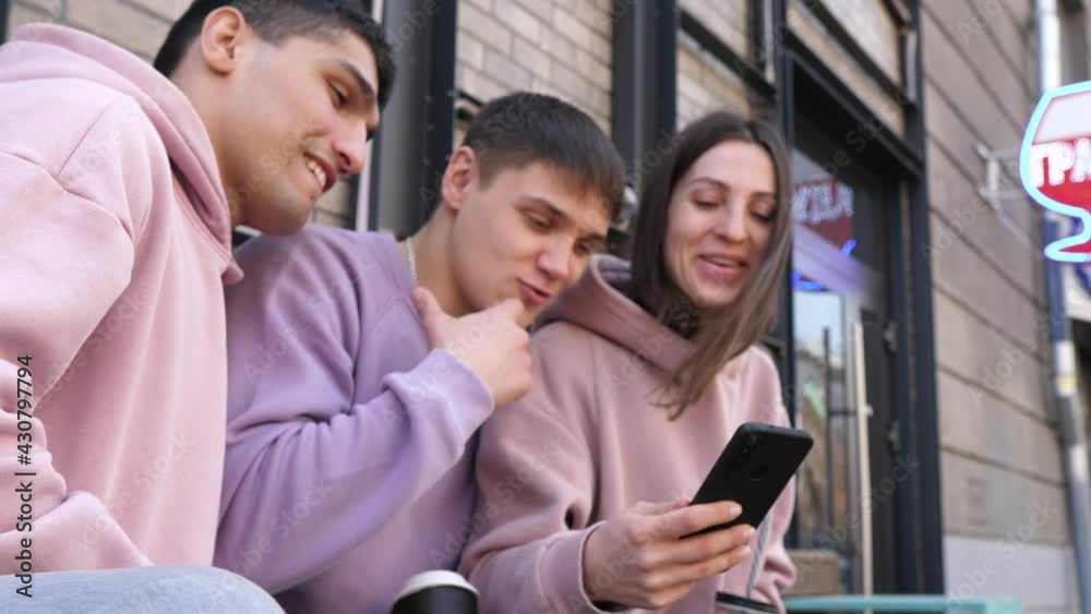 Teenage friends are laughing outside at something on their smartphone or mobile phone. Friendship, communication, youth and lifestyle concept Teenage friends are laughing outside at something on their smartphone or mobile phone. Friendship, communication, youth and lifestyle concept