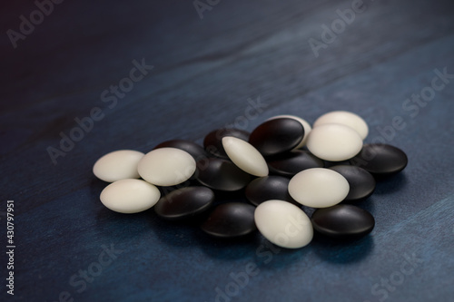 Black and white stones of traditional Chinese game go on blue table