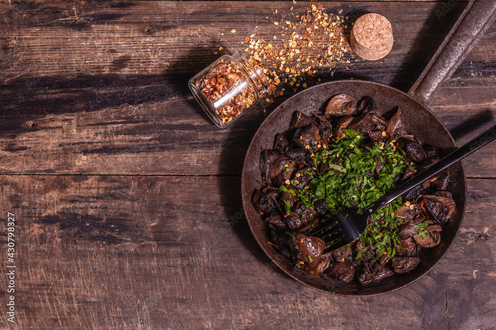 Fried royal champignons in an old cast-iron skillet with trendy hard light, dark shadow Fried royal champignons in an old cast-iron skillet with trendy hard light, dark shadow