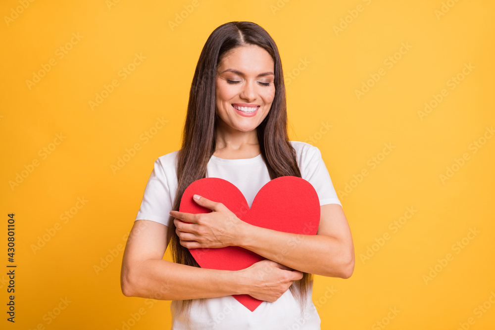 Photo portrait of woman embracing red paper heart love symbol closed eyes copyspace isolated on vibrant yellow color background Photo portrait of woman embracing red paper heart love symbol closed eyes copyspace isolated on vibrant yellow color background