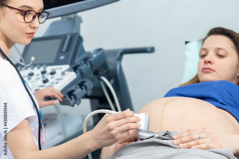 In the gynecology room, a lady doctor examines a pregnant woman using an ultrasound machine. In the gynecology room, a lady doctor examines a pregnant woman using an ultrasound machine.
