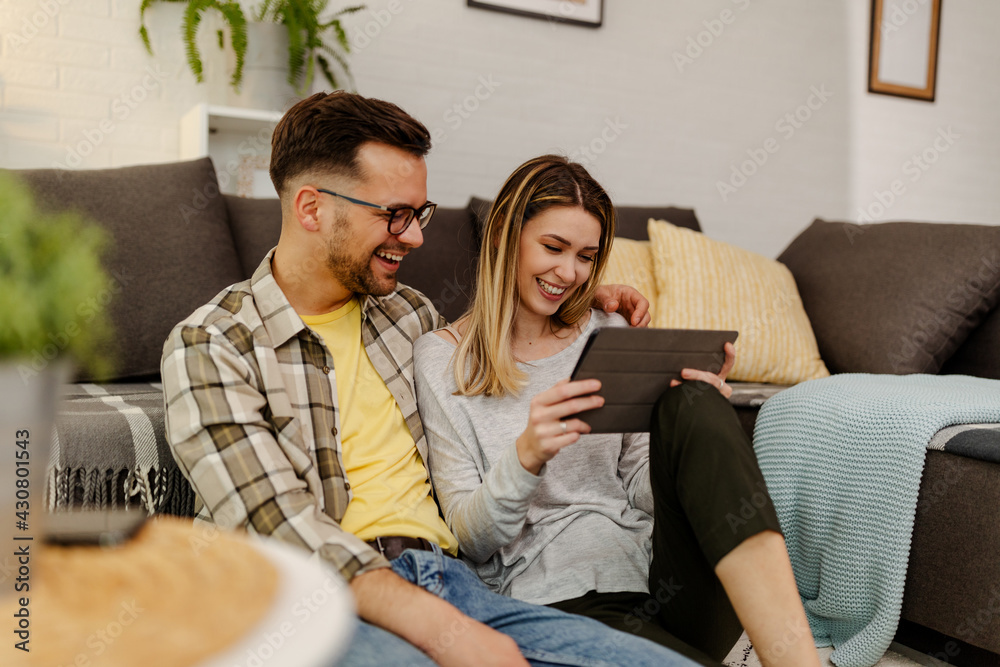 Happy couple with tablet, shopping online, making internet order sitting at home floor. Happy couple with tablet, shopping online, making internet order sitting at home floor.