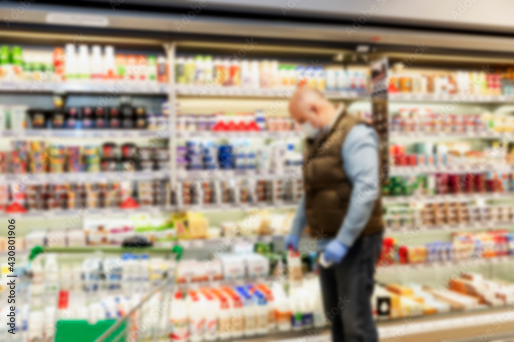 A man in a mask and gloves in a supermarket. Coronavirus pandemic. Blurred.