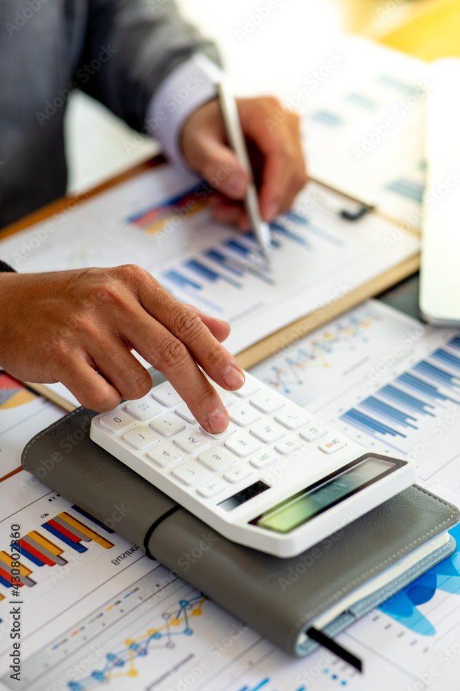 Close up Business man using calculator and laptop for do math finance on wooden desk, tax, accounting, statistics and analytical research concept