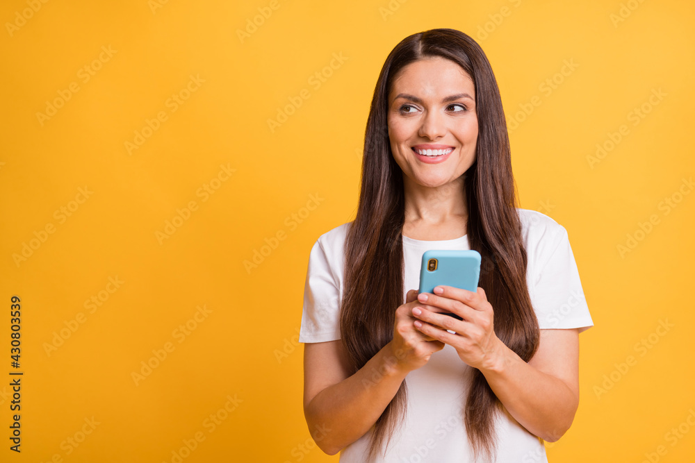 Photo portrait of woman browsing internet keeping mobile phone looking blank space isolated on vivid yellow color background