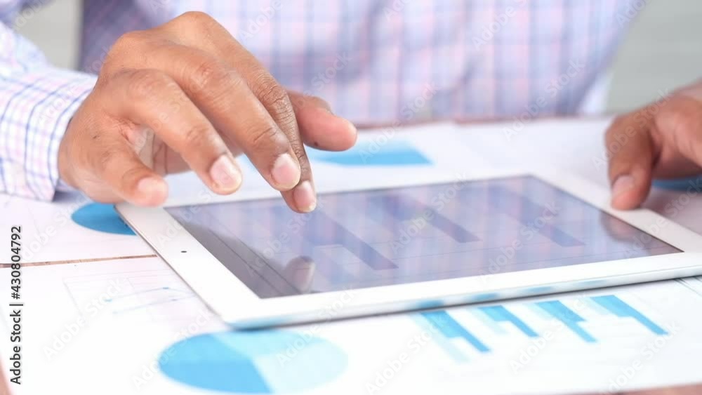 man's hand working on digital tablet at office desk, using self created chart man's hand working on digital tablet at office desk, using self created chart